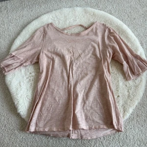 Ljusrosa topp med öppen rygg - Säljer en ljusrosa topp med trekvartsärm och snygg öppen ryggdetalj. 