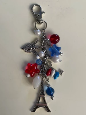 keychain/bag charm 💙🤍❤️ - Keychain/ bag charm med berlocker och pärlor, gjord av mig💙🤍❤️