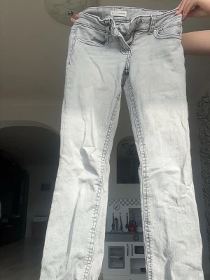 Lågmidjade jeans  - Säljer ett par ljusgrå lågmidjade jeans från Gina Tricot med femfickdesign och utsvängda nertill💖Kolla in min profil för fler fina och trendiga plagg!