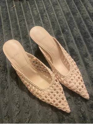 Beige flätade ballerinaskor från Zara - Säljer ett par snygga beige ballerinaskor från Zara med spetsig tå och öppen häl. Skorna har en flätad design i ett flätat material som ger en luftig och trendig look. Perfekta för dig som gillar stilrena och moderna detaljer.