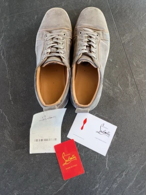 Gråa Louboutin sneakers i mocka - Snygga gråa sneakers från Christian Louboutin i mjuk mocka med klassisk låg siluett och ikonisk röd sula. Perfekta för dig som vill ha något exklusivt och stilrent. Hör gärna av dig vid frågor :) 
