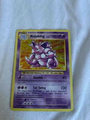 Pokémonkort Nidoking 2016 - Säljer ett samlarkort från Pokémon med Nidoking, nivå 48 och 150 HP. Kortet har lila och gula kanter, klassisk Pokémon-design och är tryckt 2016. Perfekt för dig som gillar att samla eller spela Pokémonkort.