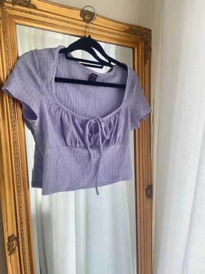 Ljuslila topp med knyt från  - Superfin ljuslila topp från Shein med korta ärmar och knyt framtill. Toppen har en lätt rynkad struktur storlek S passar XS 