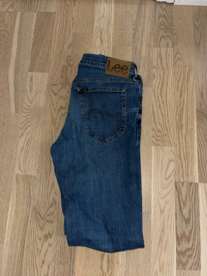 Blå Lee Daren jeans W32 L34 - Säljer ett par klassiska blå jeans från Lee, modell Daren Zip Fly. Jeansen har en rak passform, fem fickor och Lee-logga på bakfickan. Tillverkade i bomull med dragkedjegylf. Perfekta för en avslappnad och stilren look.