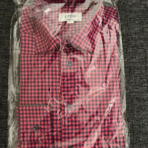 Rutig skjorta från Eton - Säljer en snygg röd och blå rutig skjorta från Eton. Skjortan har klassisk krage och knäppning framtill. Perfekt för dig som vill ha en stilren och färgglad look.