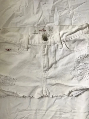 Lågmidjad vit kjol - Säljer en låg vit jeans kjol från hollister i storlek XS. Inga defekter och nästan aldrig använd pga för liten för mig.