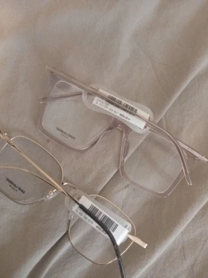 Två trendiga solglasögon i olika stilar - Säljer två par solglasögon från Michael Kors. Ett par har transparent, fyrkantig båge i ljus plast och det andra har tunn, guldig metallbåge med rundad form. Perfekta accessoarer för att lyfta din look.