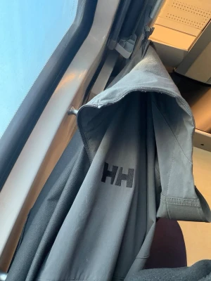 Helly Hansen grå vindjacka - Jackan är storlek M men det sitter tajt som S storlek. Snygg svart vindjacka från Helly Hansen med huva och dragkedja framtill. Modellen Blaze Softshell Hood har diskret HH-logga på bröstet och två sidofickor med dragkedja. Tillverkad i mjukt softshell-material som står emot vind och lätt regn.