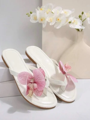 Vita sandaler med rosa blomma - Snygga vita sandaler med tårem och stor rosa orkidéblomma som dekoration framtill. Sandalerna har platt sula och är tillverkade i ett glansigt material som ger en fräsch och somrig känsla. Storlek 39 men passar som 38!