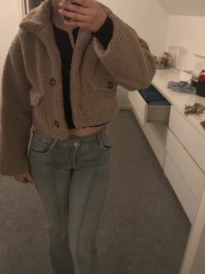 Brun/smutsrosa cropped teddyjacka ASOS DESIGN - Säljer en teddyjacka från ASOS DESIGN i croppad modell. Jackan har stora knappar framtill, två fickor med lock och mjukt satinliknande foder. Perfekt för dig som vill ha en mysig och trendig look!