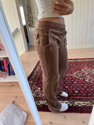 Bruna velourbyxor från Juicy Couture - Har sytt upp så de passar mig i längden, jag är 161cm lång. Metallen på snörena har rosats lite, och et är ett litet hål i bakfickan.