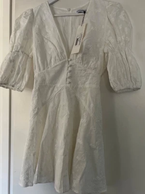 Vit kort klänning från Adoore - Supersöt vit kort klänning från Adoore! Heeelt ny med prislappen kvar!! Köpte till studenten men behöver den inte så säljer pga kan inte lämna tillbaka den längre☹️ Nypris: 1 495kr