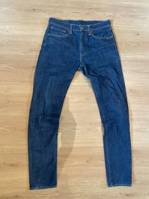 Levi's mörkblå jeans 512 - Säljer ett par klassiska mörkblå Levi's jeans. Jeansen har fem fickor, raka ben och tydliga kontrastsömmar. Ett par perfekta jeans för dig som vill ha en stilren look.                                                  Bara att höra av sig vid frågor om tex mått.                  Pris kan diskuteras vid snabb affär