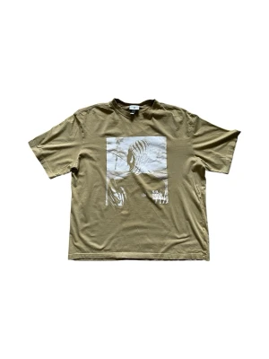 Beige T-shirt med tryck - Olivgrön t-shirt från H&M med ett stort grafiskt tryck i vitt på framsidan. Klassisk passform med rund hals och korta ärmar. Perfekt för en avslappnad och cool stil. Tillverkad i mjuk bomull som känns skön mot huden.⭐️