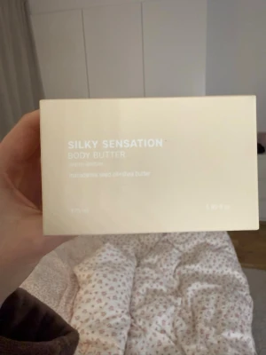 Silky Sensation Body Butter - Lyxig body butter med doft av warm amber. Innehåller macadamiafröolja och sheasmör som ger intensiv återfuktning och silkeslen känsla. Kommer i plomberad förpackning. Limiterad från kalendern och slutsåld online!