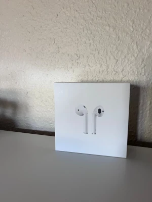 Apple AirPods gen 1 - Säljer ett par vita Apple AirPods med tillhörande laddningsetui. Trådlösa hörlurar i stilren design som passar perfekt till både musik och samtal. Kommer i originalförpackning. Smidig och kompakt form, tillverkade i plast.