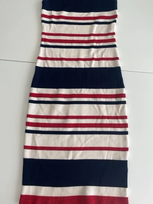 Randig klänning från Vinceotto - Snygg ärmlös klänning från Vinceotto med breda och smala ränder i marinblått, rött och vitt. Modellen är kroppsnära,  perfekt för en trendig look. Tillverkad i mjukt stickat material som känns bekvämt mot huden.