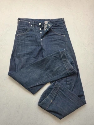 Retro! Levi's Engineered Jeans 10th - Säljer ett par retro klassiska Engineered jeans från Levi's med raka ben och knäppning fram. Jeansen har fem fickor, silverfärgade nitar och tydliga sömmar. Perfekta för dig som gillar en tidlös och avslappnad stil. Obs bilderna för detaljer.