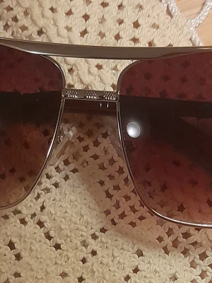 Louis Vuitton attitude pilotbågar solglasögon - Snygga solglasögon från Louis Vuitton med klassisk pilotform och guldfärgade metallbågar. Glasen är tonade i en mörk brun nyans. Kommer med originalförpackning, fodral och putsduk.