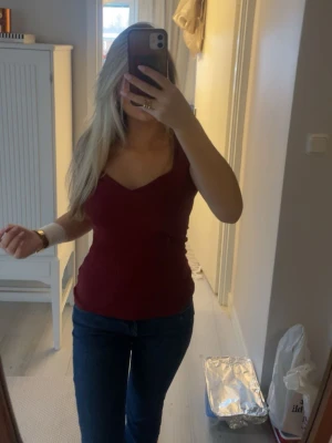 Vinröd topp med v-ringning - Snygg vinröd topp,  Toppen har en figurnära passform och är perfekt att styla med jeans eller kjol. den är ganska stretchig också 