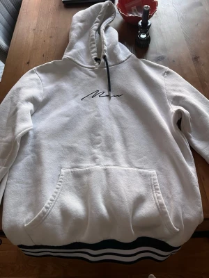 Vit hoodie från boohooMAN med tryck - Vit hoodie från boohooMAN med svart broderat tryck på bröstet och svarta dragsnören i huvan. 