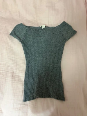 Grå ribbad offshoulder topp - Snygg grå ribbad topp med offshoulder-design och korta ärmar. Stretchigt material som sitter tight och framhäver figuren. 