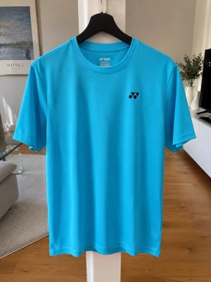 Blå sport t-shirt från Yonex - Snygg blå sport t-shirt från Yonex. Passar perfekt till träning eller varmt väder och en fräsch outfit!