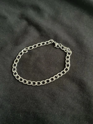 Silvrigt kedjearmband i metall - Stilrent armband i silverfärgad metall med klassisk kedjedesign. Länkarna är ovala och armbandet har ett enkelt spänne. Perfekt för dig som gillar minimalistiska accessoarer med lite edge.