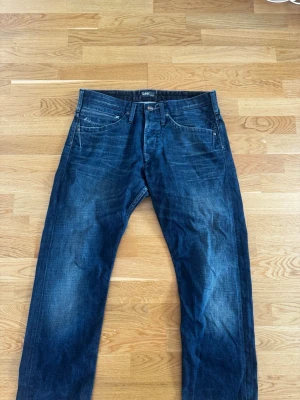 Lee Jeans - Lee Jeans – Storlek 33/34 – Mörkblå tvätt  Säljer ett par snygga och välvårdade Lee-jeans i storlek W33/L34. Klassisk mörkblå tvätt med naturligt slitna detaljer som ger en stilren och tidlös look. Perfekta för både vardag och mer uppklädda tillfällen.  Detaljer:  * Märke: Lee * Storlek: 33/34 (W33/L34) * Färg: Mörkblå denim * Modell: Rak/slim passform * Klassisk 5-ficksdesign * Gylf med knapp och dragkedja * Fina naturliga slitningar och tvättningar * Hela och i gott använt skick * Bekvämt deni