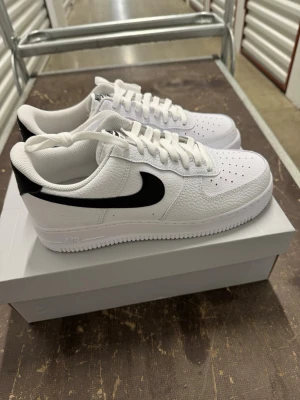 Nike Air Force 1 '07 Vit/Svart strl 42 - Helt nya Nike Air Force 1 '07 Vit/Svart strl 42 Skorna har inte blivit använda.   Nypris hos Nike 1400 kr