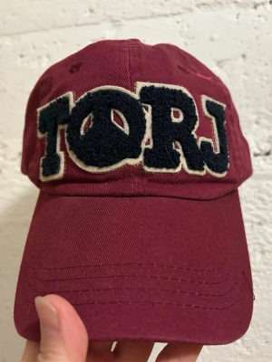 Vintage Retro keps - Snygg vinröd keps med stora, broderade bokstäver 'TORJ' i svart och vitt framtill. Justerbart spänne bak i läder och texten 'FREEDOM' broderad ovanför öppningen. Perfekt accessoar för en avslappnad streetwear-look. 100kr/st . Samma frakt 