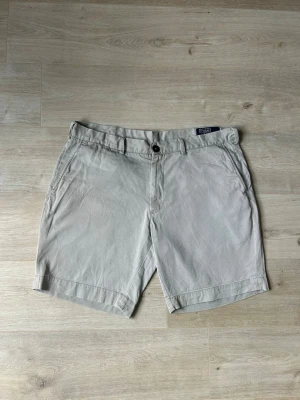 Beiga Ralph Lauren Chinosshorts Shorts Chinos Storlek W38 - Mycket fina Ralph Lauren shorts i beige färg | Jeansen är i mycket bra skick och sparsamt använda. |  Äkta som allt annat jag säljer! ✅ |  Storlek: W38 | Skick: Mycket Bra Skick - Har tyvärr en liten slitning (SE SISTA BILD) | Färg: Beige | Märke: Ralph Lauren| Modell: Shorts |   Hör gärna av dig vid frågor så svarar jag så fort jag kan! 😁 |  (SKU - 182)