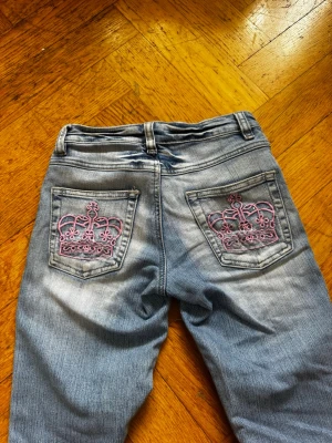 Blå bootcut jeans från Revers - Snygga blå bootcut jeans från Revers med slitningar och broderad detalj på fickan. Jeansen har klassisk femficksdesign, knappgylf och en cool tvättad look. Perfekta för dig som gillar en avslappnad och trendig stil.