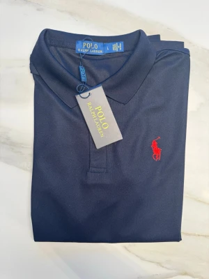 Ralph Lauren Piké - Mörkblå Ralph Lauren Piké med röd häst logga i storlek L (passar runt 170-176). Kom privat med frågor och prisförslag😊