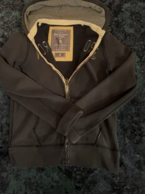 Abercrombie & Fitch  - Storlek S men den är stor i storlek så hade nog sagt M-, ser ut att vara skavanker men den är gjord så de är en gammal vintage hoodie, en mörkblå hoodie med gråa toner, pris är inte hugget 