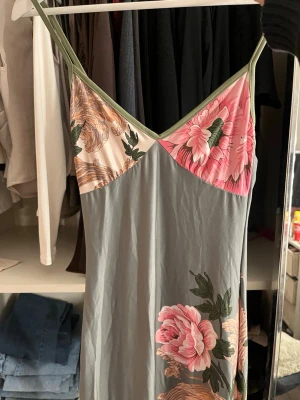 Klänning med blommigt mönster från shein - Snygg klänning med tunna axelband och v-ringning. Överdelen har ett färgstarkt blommönster i rosa, grönt och beige. Lång modell med mjukt, följsamt tyg som känns skönt mot huden. Perfekt för mysiga kvällar