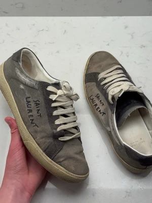Saint Laurent grå sneakers - | saint Laurent Sl/06 | | fint skick | Storlek: 41 sitter som 41-42. | Nypris: ≈ 8000 Kr | Mitt pris: 1999 Kr | Ingår: bara skorna | Fraktar via PostNord eller InstaBox på köparens bekostnad | Pris kan diskuteras vid snabb affär! 
