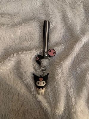 Kuromi och Hello Kitty nyckelringar - Två söta nyckelringar med Kuromi och Hello Kitty från Sanrio. Kuromi-nyckelringen har svart och rosa detaljer samt en figur i mjukt gummi. Hello Kitty-nyckelringen är lila med text och har en liten blomma som extra detalj. Perfekt att hänga på väskan eller nycklarna. Bundle!!