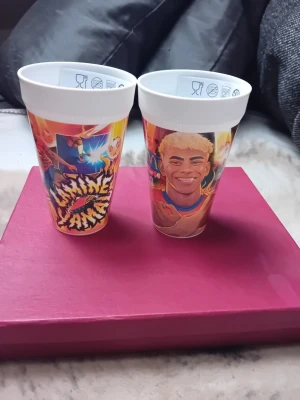 McDonald's lamine yamal - Två vita plastmuggar från McDonald's med färgglada motiv av tecknade figurer och texten 'lamine yanal'. Muggarna har tryck i rött, gult och blått och är perfekta för samlare eller som roliga dryckesglas. Levereras i originalförpackning. En för 200kr