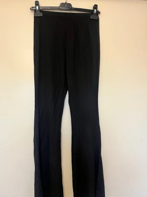 Svarta ribbade leggings - Säljer ett par svarta leggings med ribbad struktur. De har hög midja och är stretchiga för en bekväm och tight passform. Perfekta att styla med oversized tröja eller crop top. Passar dig som gillar enkel men trendig stil.