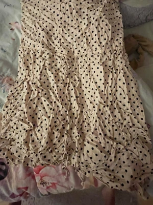 Beige prickig kortklänning Divided - Söt beige kortklänning från Divided med svarta prickar. Klänningen har en avslappnad passform och är perfekt för varma dagar. Tillverkad i ett lätt material som känns skönt mot huden. Supersnygg till sneakers eller sandaler.