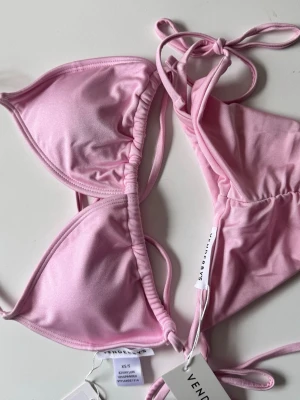 Ljusrosa bikini från Venderbys - Supersöt ljusrosa bikini från Venderbys med klassisk trekantsmodell och tunna knytband. Bikinin är helt oanvänd och ligger i förpackning. Nypris 500 SEK