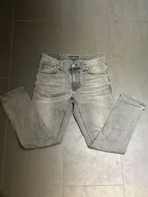 Nudie Jeans - Beskrivning Nudie Jeans av modellen Lean Dean Storlek: 28/32 men passar mer som 28/30.  - Skicket på jeansen är ny utan prislapp 10/10 - mitt pris: 429 -Nypris: 1599kr.   En av fördelarna med Nudie jämfört med till exempel Replay, Tiger of Sweden, Dondup och Jacob Cohen är att om eventuella defekter skulle uppstå någon gång så finns möjlighet att lämna in plaggen hos en Nudie-butik, där kostnadsfria reparationer erbjuds.