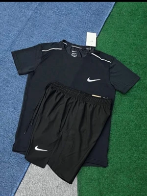 Svart träningsset från Nike - Säljer ett svart träningsset från Nike med t-shirt och shorts. T-shirten har vita detaljer vid axlarna och Nike-logga på bröstet. Shortsen har resår i midjan och vit Nike-logga på benet. Perfekt för gym eller löpning.