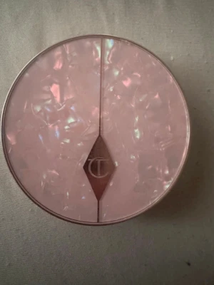 Lyxig bronzer i pärlemorrosa dosa - Säljer en bronzer från Charlotte Tilbury i en rund, pärlemorrosa dosa med elegant CT-logga. Själva bronzern har en varm, gyllenbrun ton med lätt skimmer och pressat mönster. Perfekt för att skapa glow och solkysst look.