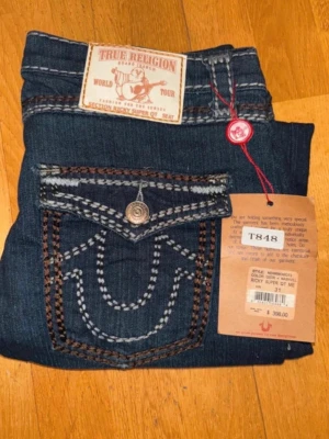 True Religion mörkblå jeans - Helt oanvända True Religion Ricky Super QT-jeans med originalprislappar kvar.  • Storlek: W31 (M) • Made in USA • 100 % bomull • Nyskick – aldrig använda  Mått (mätta plant): • Midja: 40 cm • Innerbenslängd: 76 cm • Benlängd fram: 97 cm • Benlängd bak: 102 cm