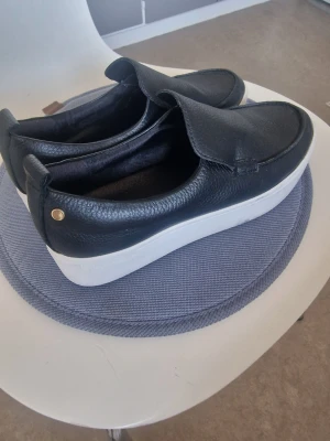 Agnes Cecilia slip-ons I äkta läder -  Säljer ett par fina och bekväma slip-ons i äkta läder från Agnes Cecilia. Använda endast cirka 5 gånger och i mycket fint skick. Nypris ca 2 000 kr. Perfekta för dig som vill ha en stilren och modern look.