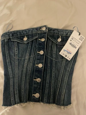 Mörkblå denim korsett med knappar - Jag säljer en väldigt snygg jeans topp från Zara. Den är aldrig använd då den inte passa mig, prislappen sitter kvar, meddela vid frågor💕