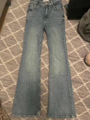 Ljusblå bootcut jeans med rå kant - Snygga ljusblå jeans med bootcut-modell och rå, fransad kant nertill. Jeansen har klassisk femficksdesign och är tillverkade i denim med lätt stretch. Perfekta för dig som gillar en avslappnad men trendig look. Köpte den för 300kr men säljer för 170kr, pris kan diskuteras. Har aldrig använt den, köpte den förra sommaren men den va för stor så den passar dig som har 34,36/xs,s i byxor 