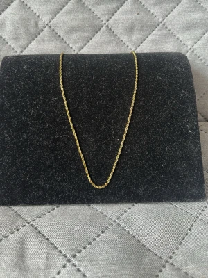 Guldigt tvinnat halsband - Snyggt halsband i guldfärgad metall med tvinnad kedja. Enkelt och stilrent smycke som passar perfekt till att lyfta vilken outfit som helst. Kedjan har ett klassiskt lås och är tunn men ändå iögonfallande. 50cm. Checka in min profil för passande armband.